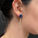 Round blue studs with silver drop shown on  an ear.